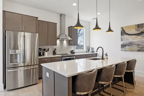 a kitchen with stainless steel appliances a sink a kitchen island a stove a table and chairs