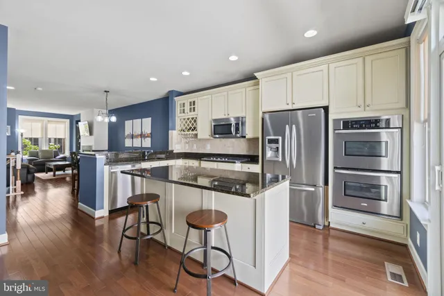 a kitchen with a refrigerator a stove and a dining table with wooden floor