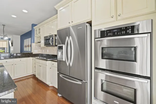 a kitchen with stainless steel appliances white cabinets white stove a refrigerator and a granite counter tops