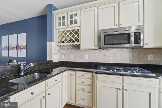 a kitchen with granite countertop white cabinets and stainless steel appliances