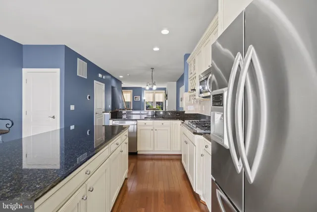 a kitchen with stainless steel appliances granite countertop a refrigerator a stove and a sink