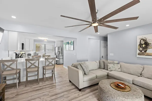 a living room with furniture a wooden floor and a ceiling fan