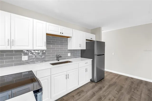 a kitchen with stainless steel appliances granite countertop a refrigerator a stove a sink and a granite counter tops with wooden floors