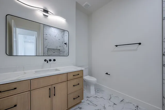 a bathroom with a toilet a sink a mirror and vanity