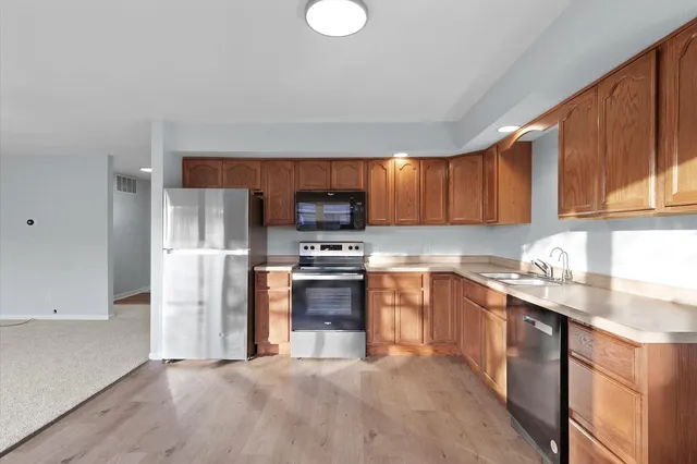 a kitchen with stainless steel appliances granite countertop a refrigerator stove top oven a sink and dishwasher