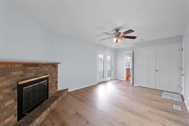 an empty room with fan and a fireplace