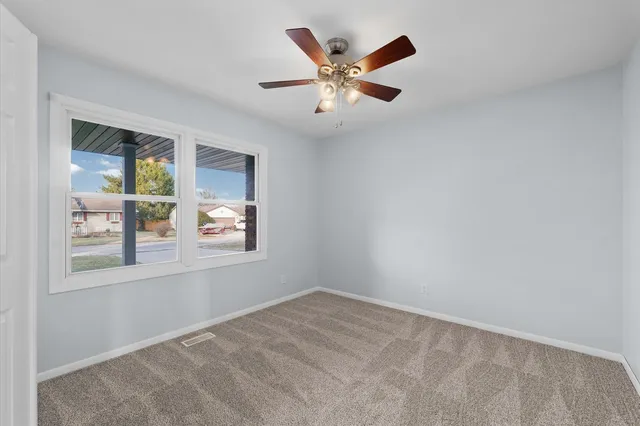 an empty room with window and ceiling fan