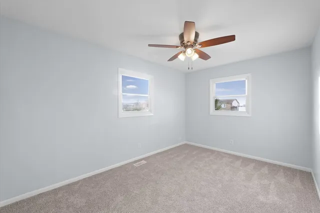 an empty room with a window and a fan