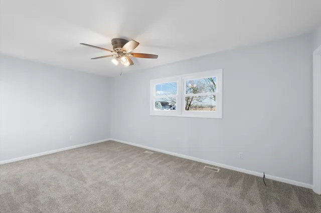 an empty room with a window and a ceiling fan