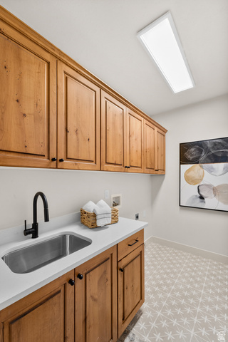 340 Brayden Way Draper, UT 84020 - Photo 33 of 58 Wood-finish cabinetry, stainless steel sink, solid surface countertop, matte black faucet, and patterned floor tile