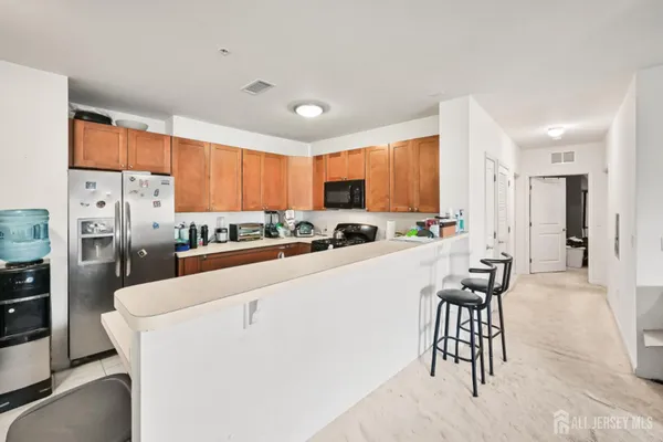 a kitchen with stainless steel appliances a refrigerator a sink a stove a table and chairs