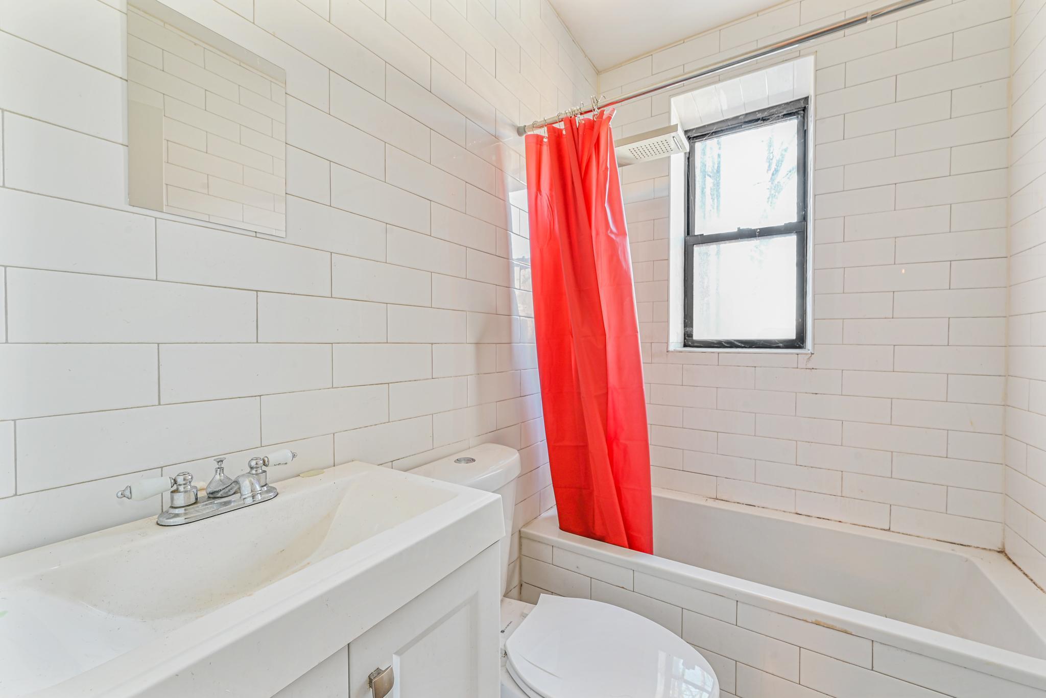 2243 Bathgate Avenue Bronx, NY 10457 - Photo 11 of 26 Full bathroom featuring tile walls, vanity, toilet, and shower / bath combo with shower curtain