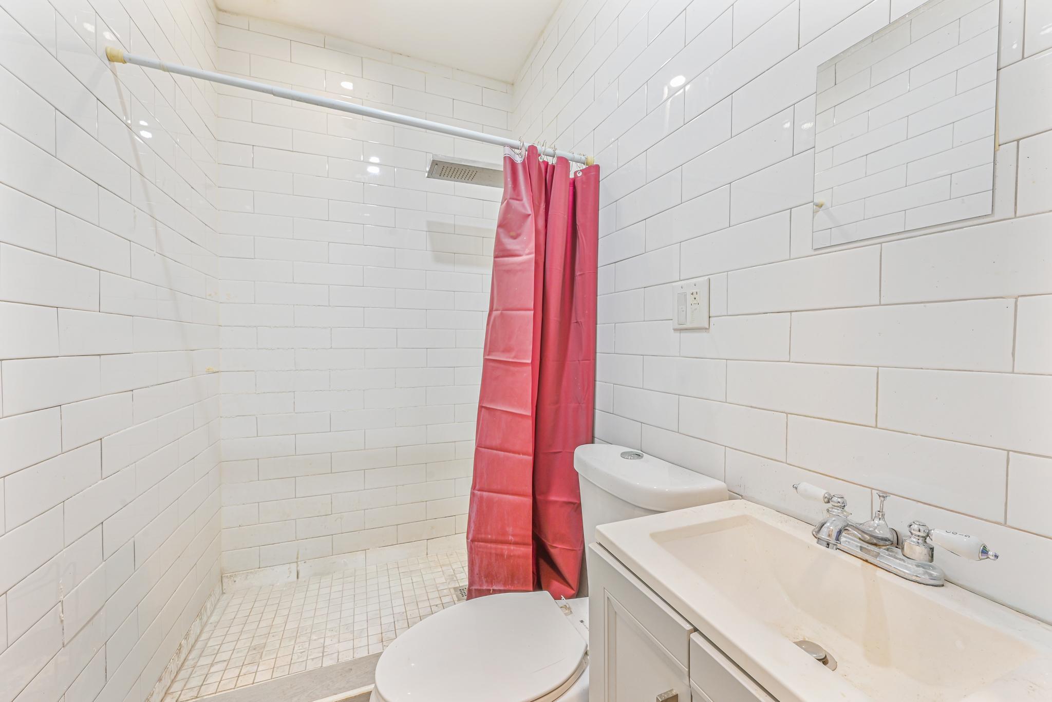 2243 Bathgate Avenue Bronx, NY 10457 - Photo 12 of 26 Bathroom with vanity, toilet, a shower with shower curtain, and tile walls