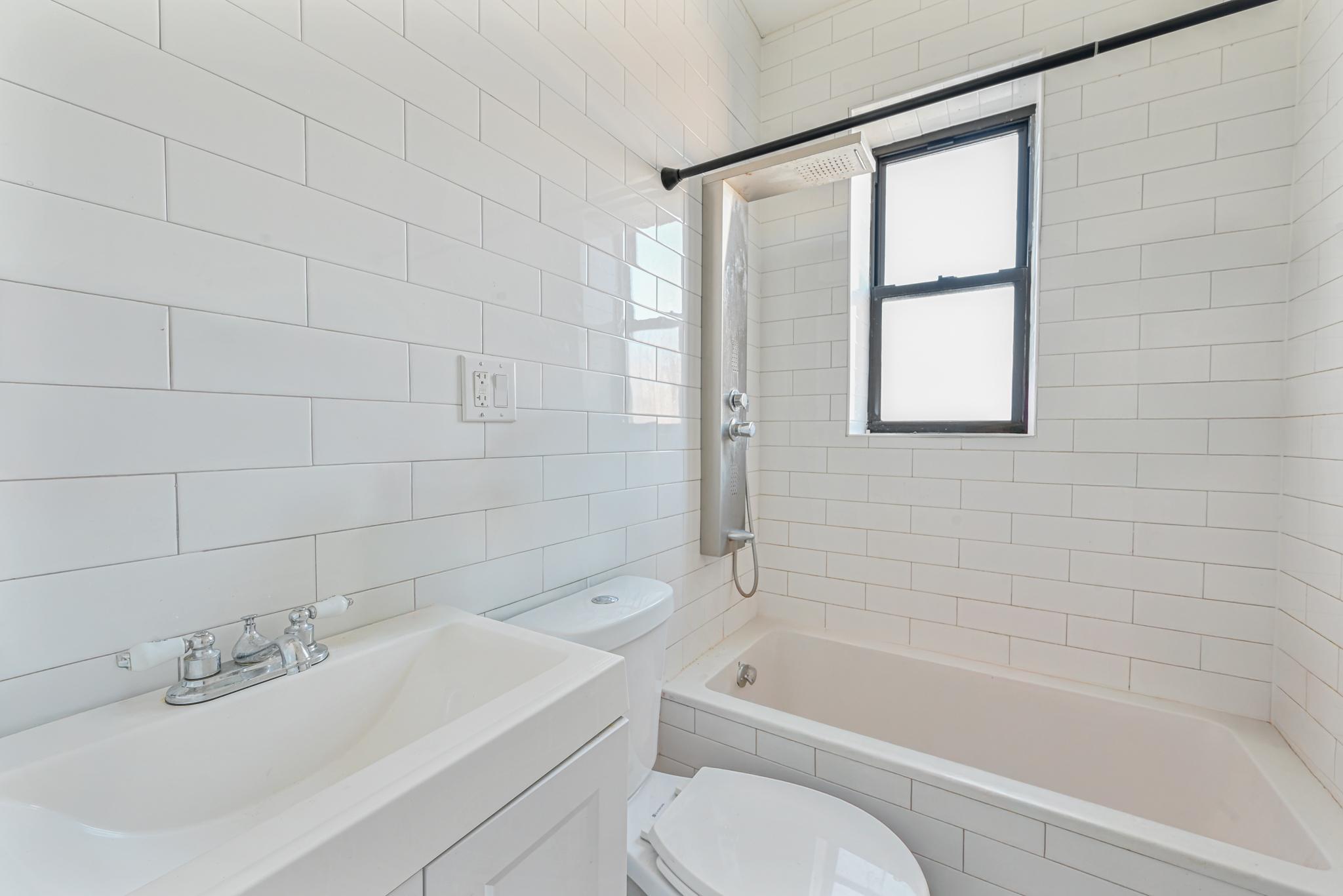 2243 Bathgate Avenue Bronx, NY 10457 - Photo 20 of 26 Full bathroom featuring tiled shower / bath, tile walls, vanity, and toilet