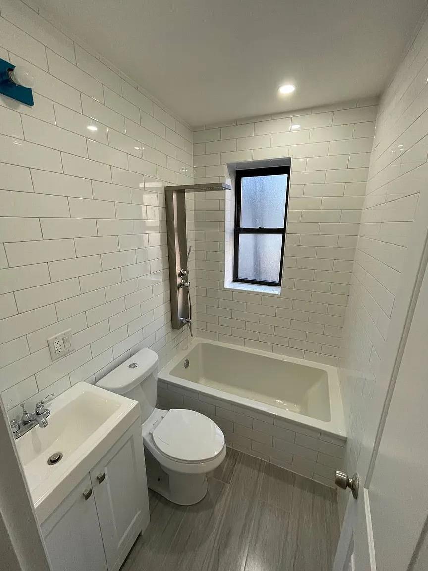 2243 Bathgate Avenue Bronx, NY 10457 - Photo 25 of 26 Bathroom featuring hardwood / wood-style floors, vanity, toilet, and tile walls