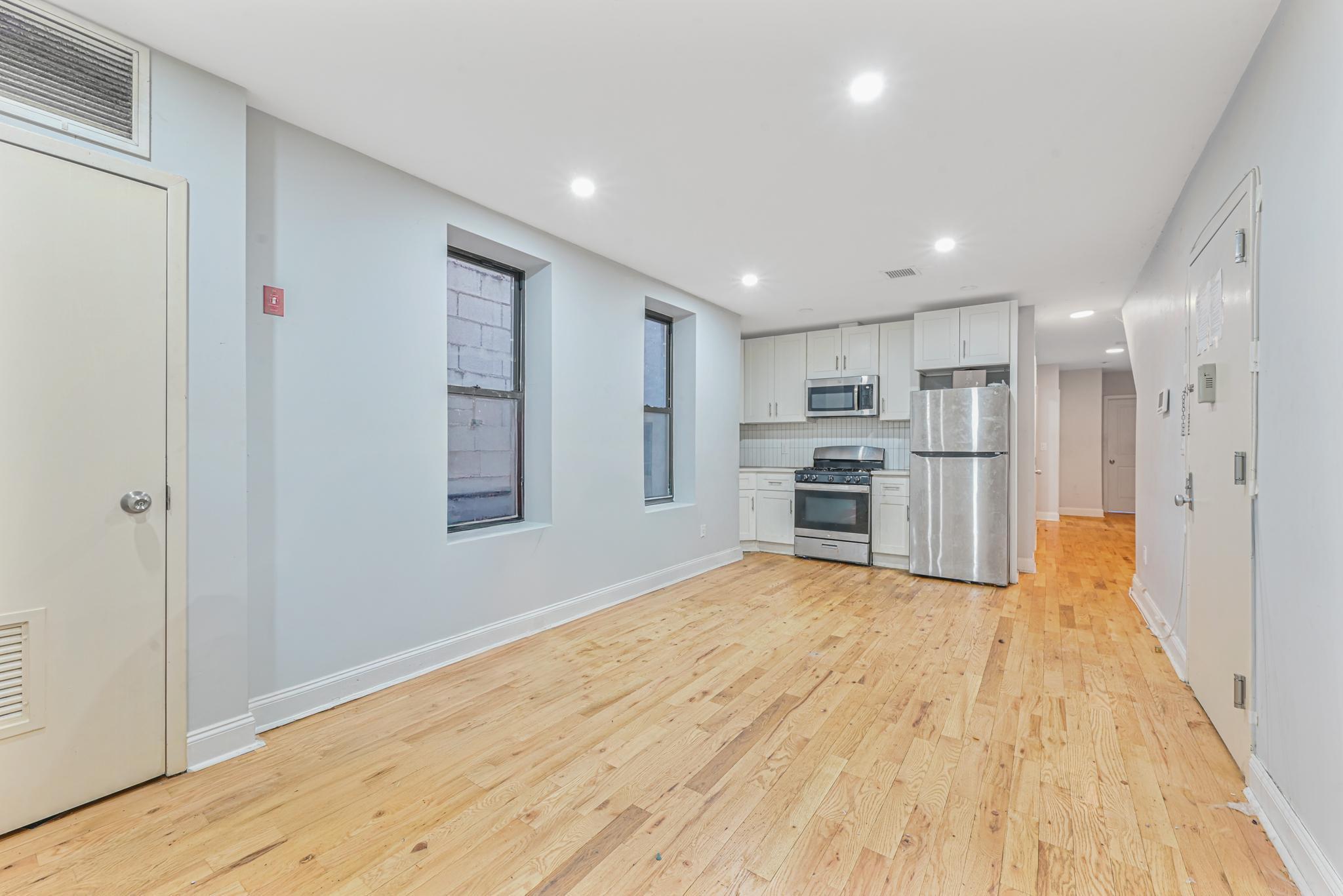 2243 Bathgate Avenue Bronx, NY 10457 - Photo 4 of 26 Kitchen featuring light wood-type flooring, white cabinets, and appliances with stainless steel finishes