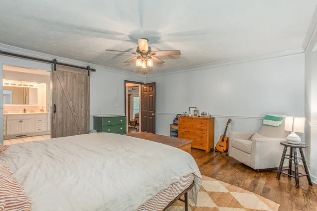a bedroom with a bed a couch and potted plant on the dresser