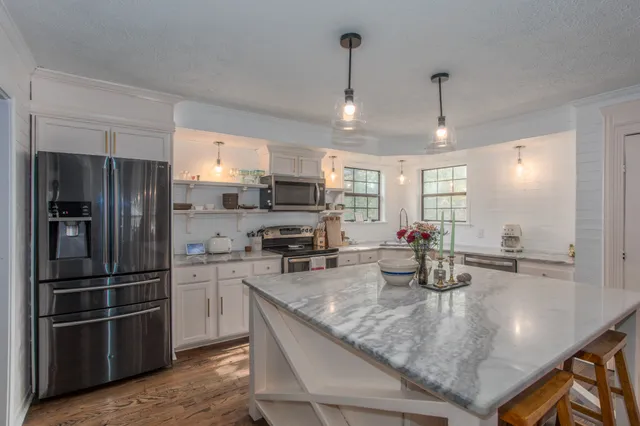 a kitchen with refrigerator a sink a counter space and stainless steel appliances