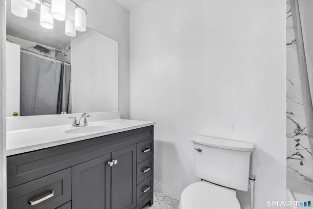 a bathroom with a granite countertop toilet sink and mirror