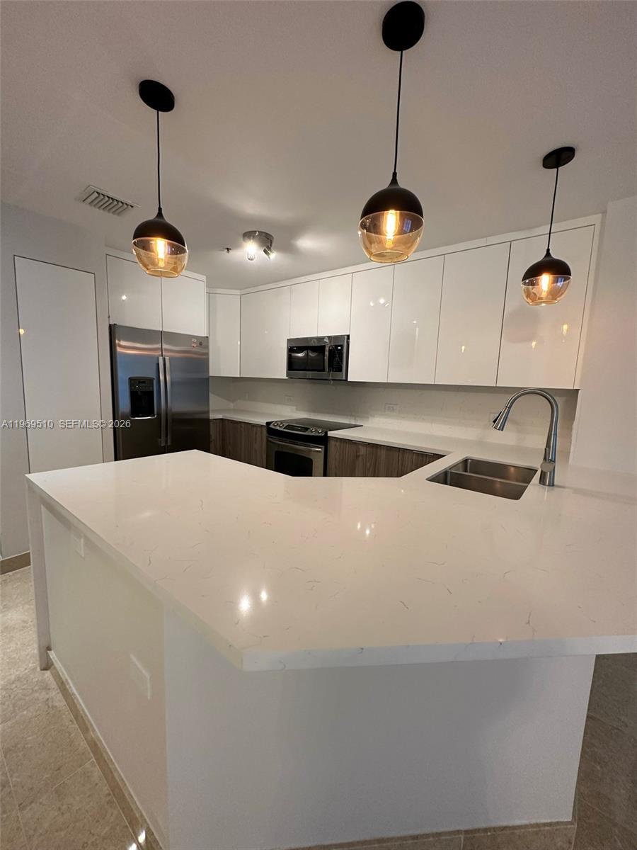 801 Brickell Key Boulevard, Unit 809 Miami, FL 33131 - Photo 4 of 17 a kitchen with stainless steel appliances granite countertop a stove a refrigerator a sink with a dining table and chairs