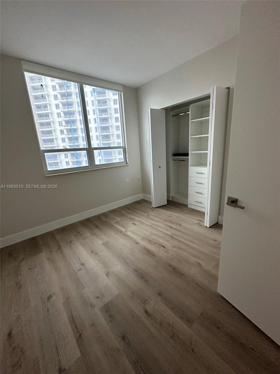 801 Brickell Key Boulevard, Unit 809 Miami, FL 33131 - Photo 10 of 17 an empty room with wooden floor and windows
