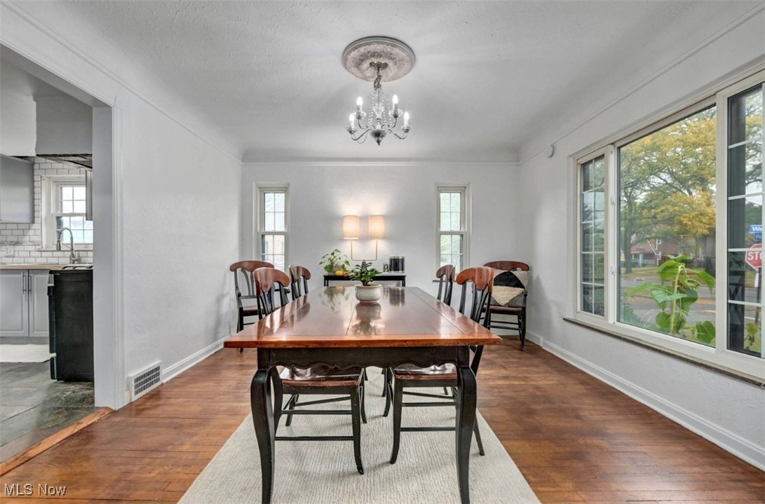 3693 Warren Road Cleveland, OH 44111 - Photo 11 of 37 Dining area featuring plenty of natural light, dark wood-type flooring, a chandelier, and a textured ceiling