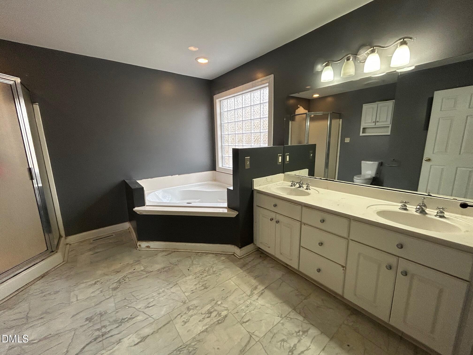 1220 Oxford Loop Road Oxford, NC 27565 - Photo 17 of 30 a bathroom with double vanity sink a two mirror a window and a bathtub