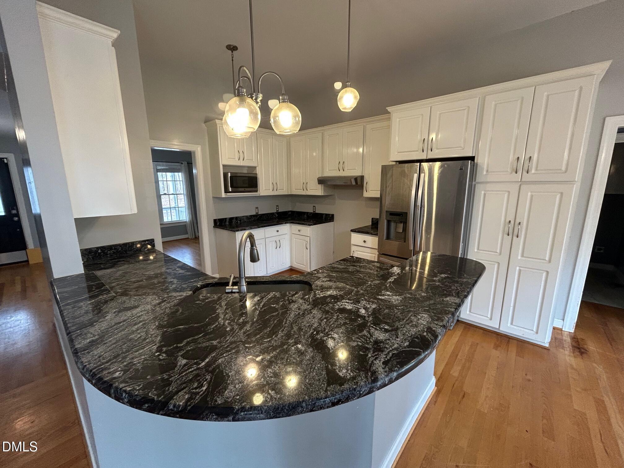 1220 Oxford Loop Road Oxford, NC 27565 - Photo 8 of 30 a kitchen with stainless steel appliances a refrigerator a stove a sink and white cabinets with wooden floor