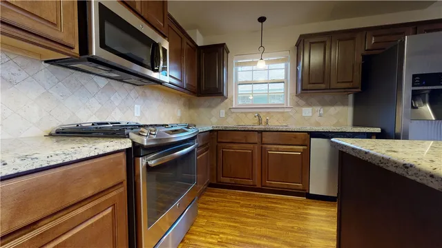 a kitchen with stainless steel appliances granite countertop wooden floors and sink