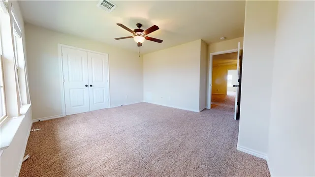 an empty room with windows and fan