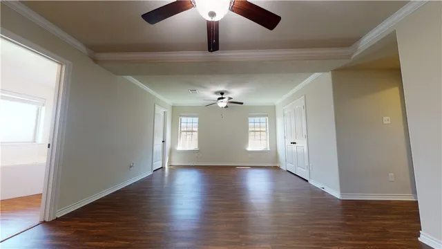 a view of an empty room with a window and wooden floor