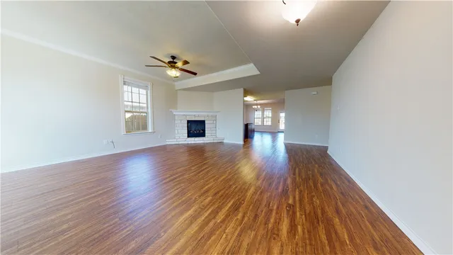an empty room with wooden floor ceiling fan and windows