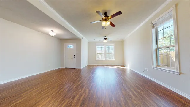 an empty room with wooden floor chandelier fan and windows