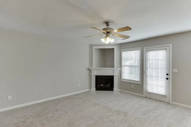 an empty room with windows fireplace and fan