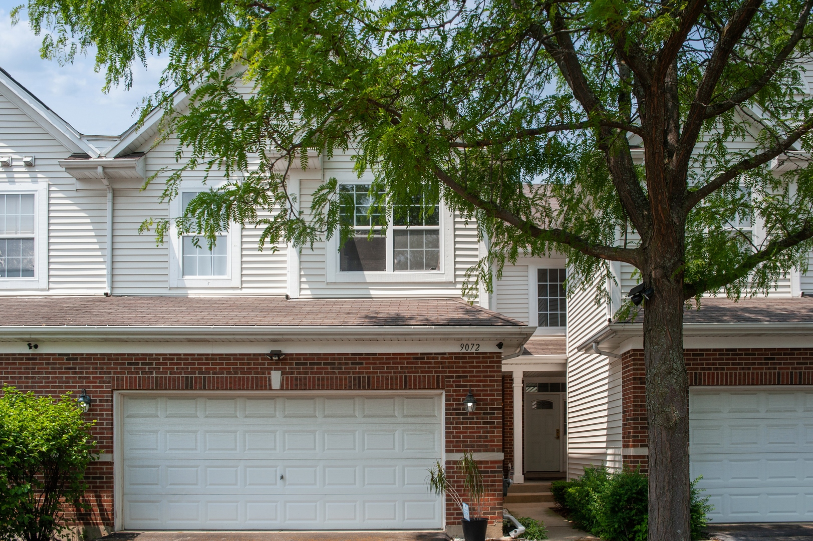 a front view of a house with a tree