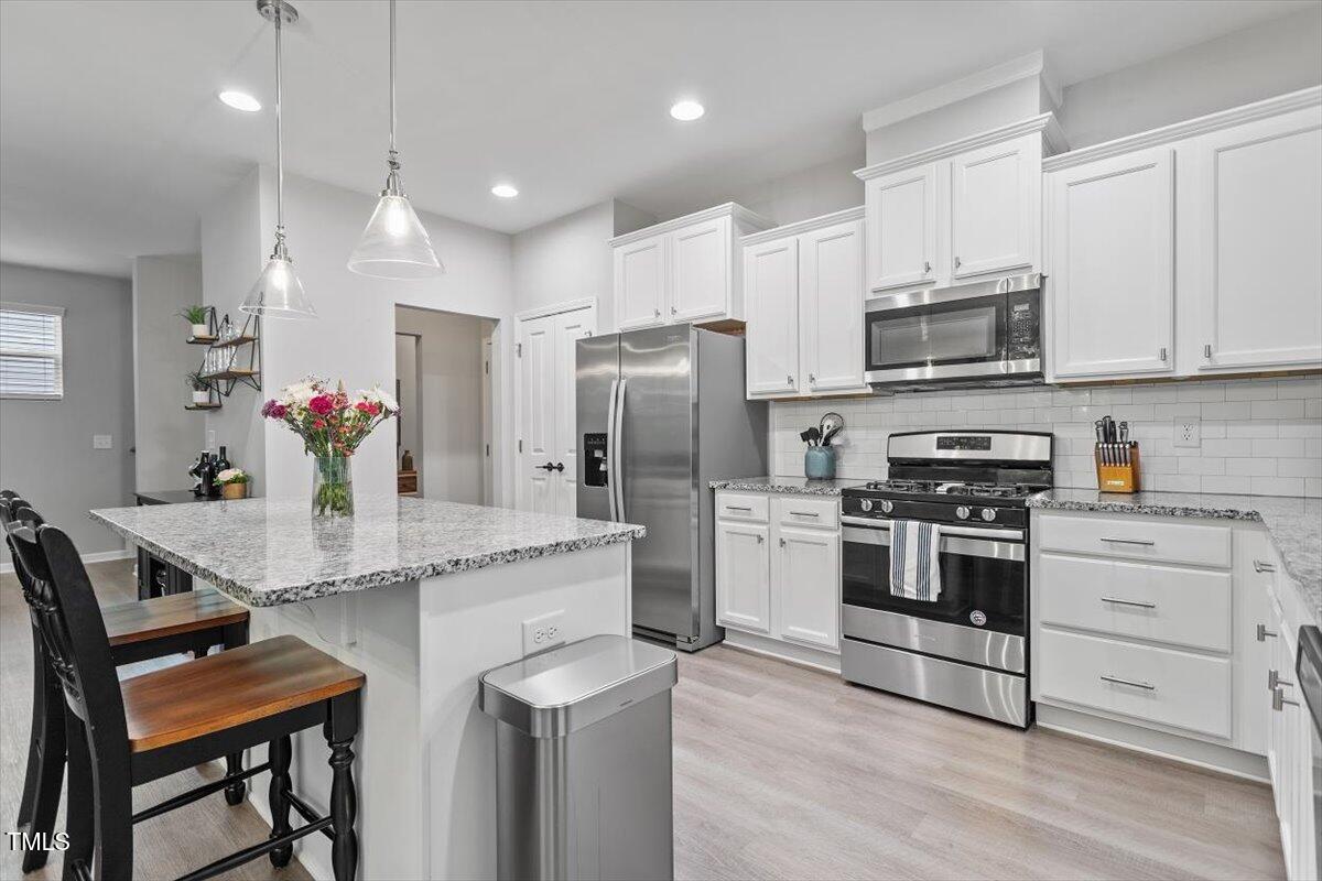 320 Everly Mist Way Wake Forest, NC 27587 - Photo 4 of 34 a kitchen with stainless steel appliances kitchen island granite countertop a refrigerator and a stove top oven