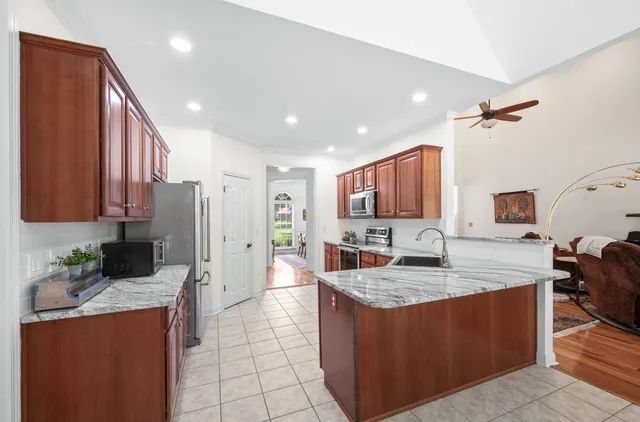 a kitchen with stainless steel appliances granite countertop a stove a sink a refrigerator and a wooden cabinets
