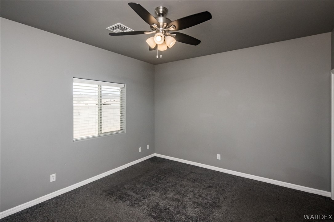 3621 North Kenneth Road Kingman, AZ 86409 - Photo 24 of 47 an empty room with a chandelier fan and windows
