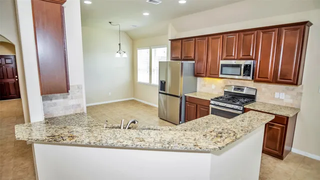 a kitchen with kitchen island granite countertop wooden cabinets and a refrigerator
