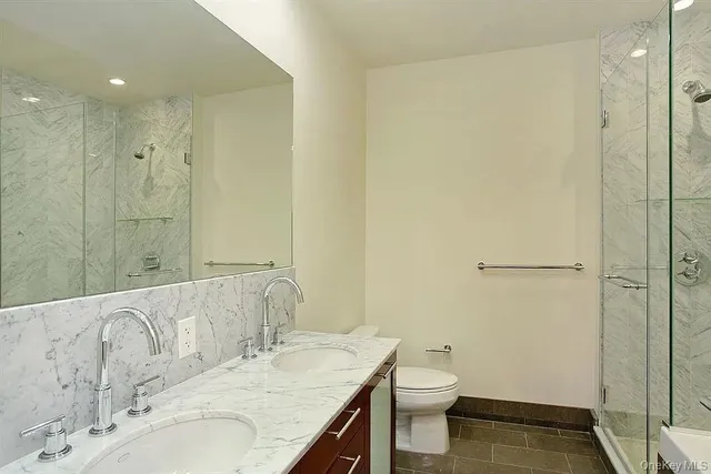 a bathroom with a granite countertop sink a toilet and shower