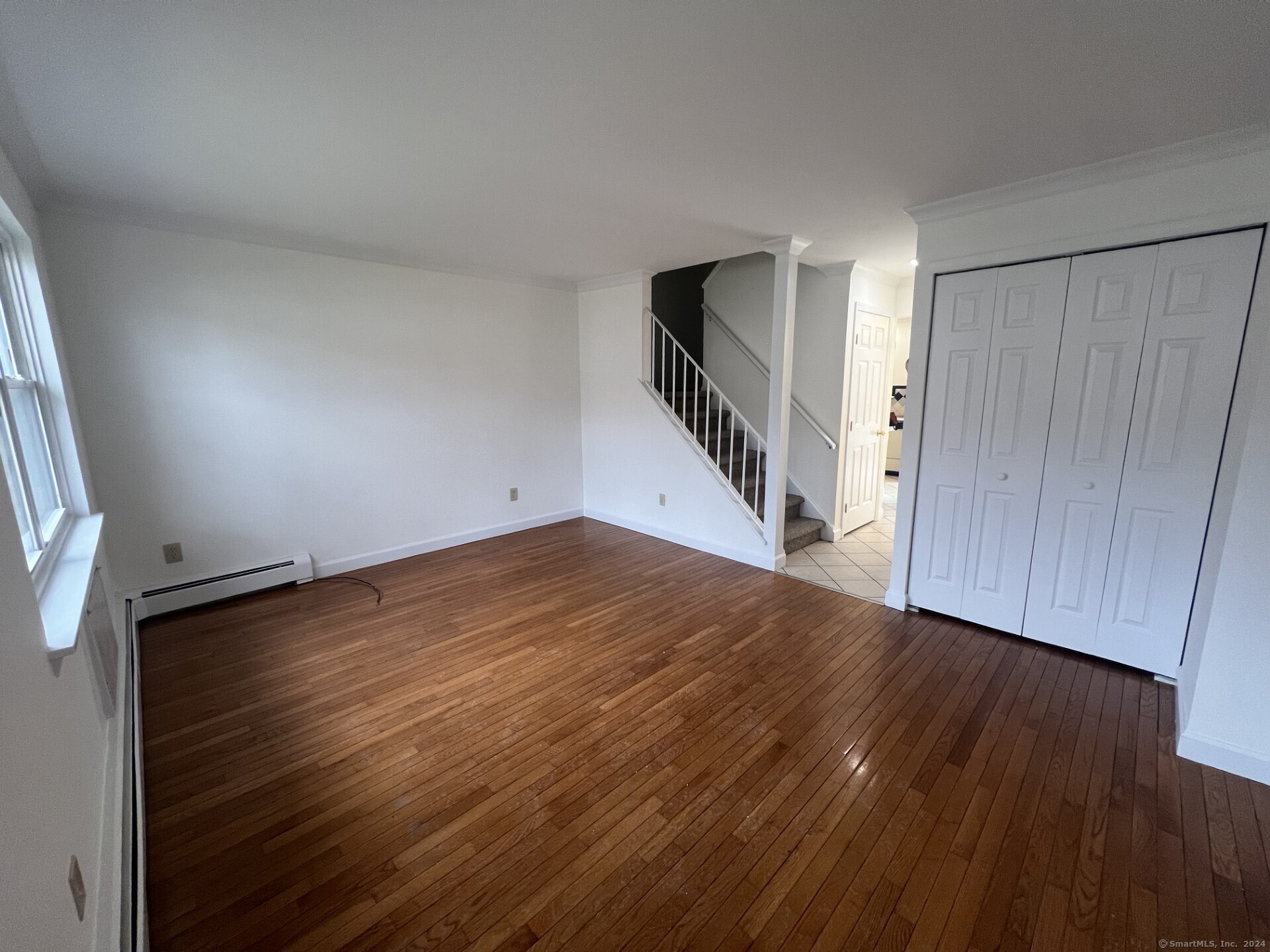 an empty room with wooden floor and stairs