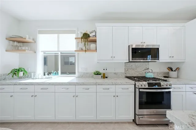 a kitchen with stainless steel appliances granite countertop a refrigerator stove and white cabinets