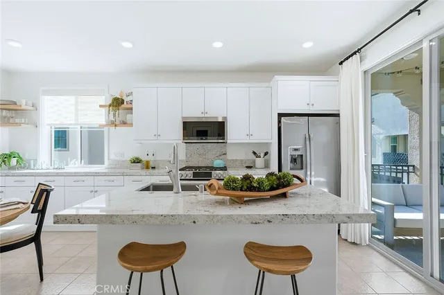 a kitchen with stainless steel appliances granite countertop a stove top oven a sink a dining table and chairs