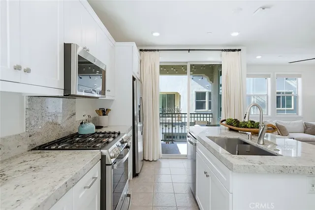 a kitchen with granite countertop stainless steel appliances a sink a stove top oven a counter space and cabinets