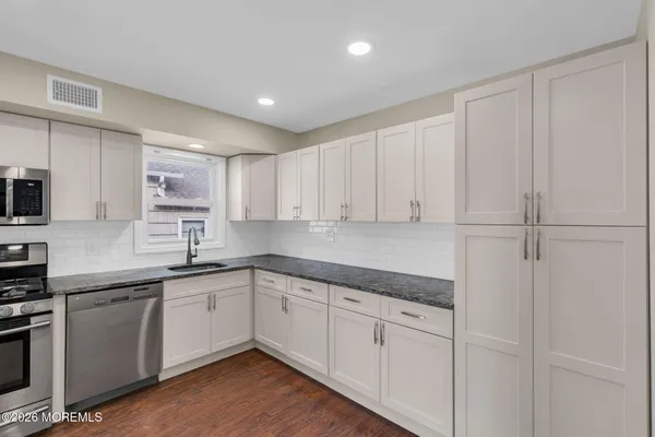 a kitchen with a sink white cabinets and white appliances