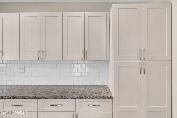 a kitchen with granite countertop white cabinets and white stainless steel appliances