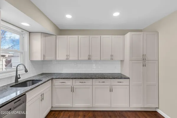 a kitchen with granite countertop white cabinets and stainless steel appliances