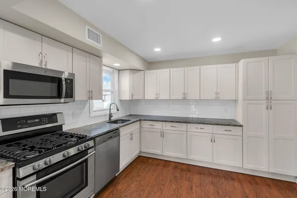 a kitchen with stainless steel appliances granite countertop a stove a sink and a microwave