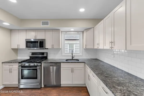 a kitchen with granite countertop a sink stainless steel appliances and cabinets