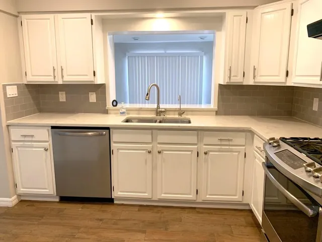 a kitchen with stainless steel appliances granite countertop a stove a sink and a microwave